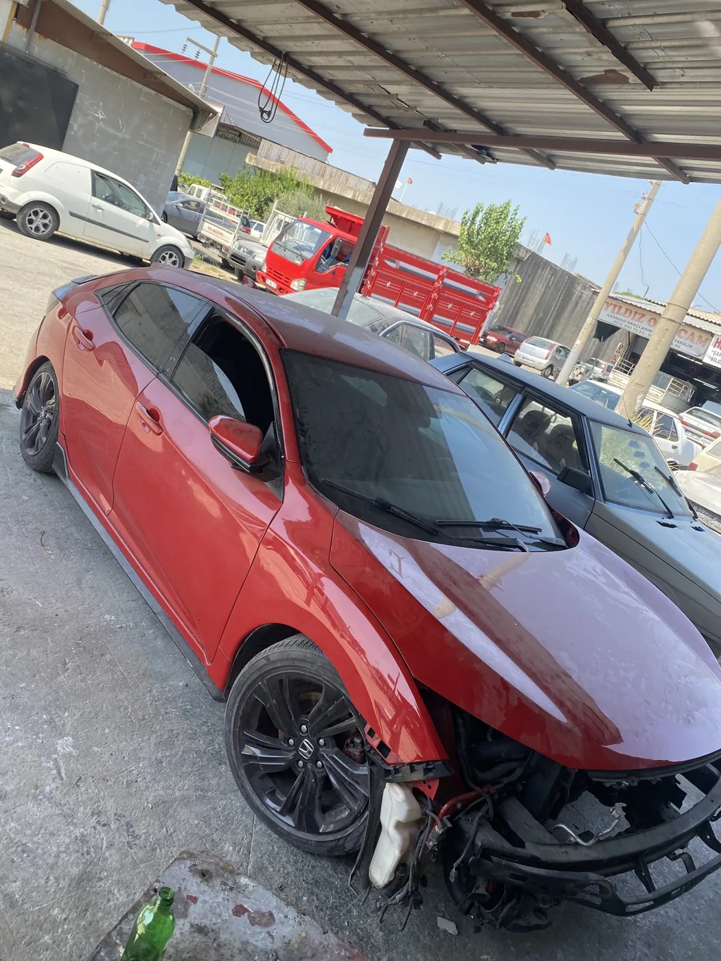 Aynı kırmızı Honda otomobilin atölyede kaporta onarımı sırasında görünümü